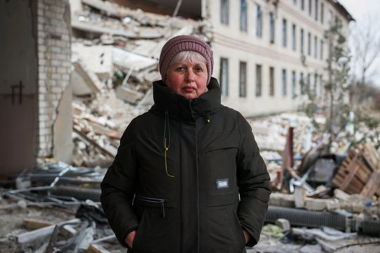 Ukrainos mokytoja Liudmila Polovko stovi prie savo mokyklos, kurią sunaikino Rusijos raketa.