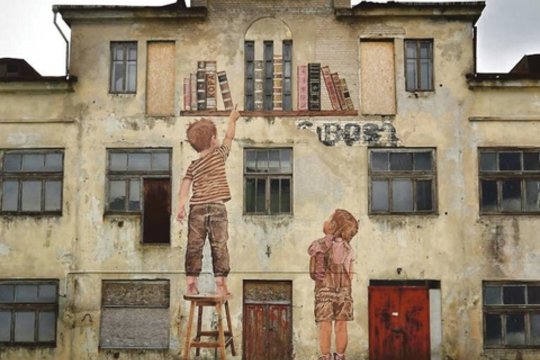 Kampo gatvėje esančio sandėlio fasadą neatpažįstamai pakeitė gatvės meno kūrinys „Knygos ir vaikai“.