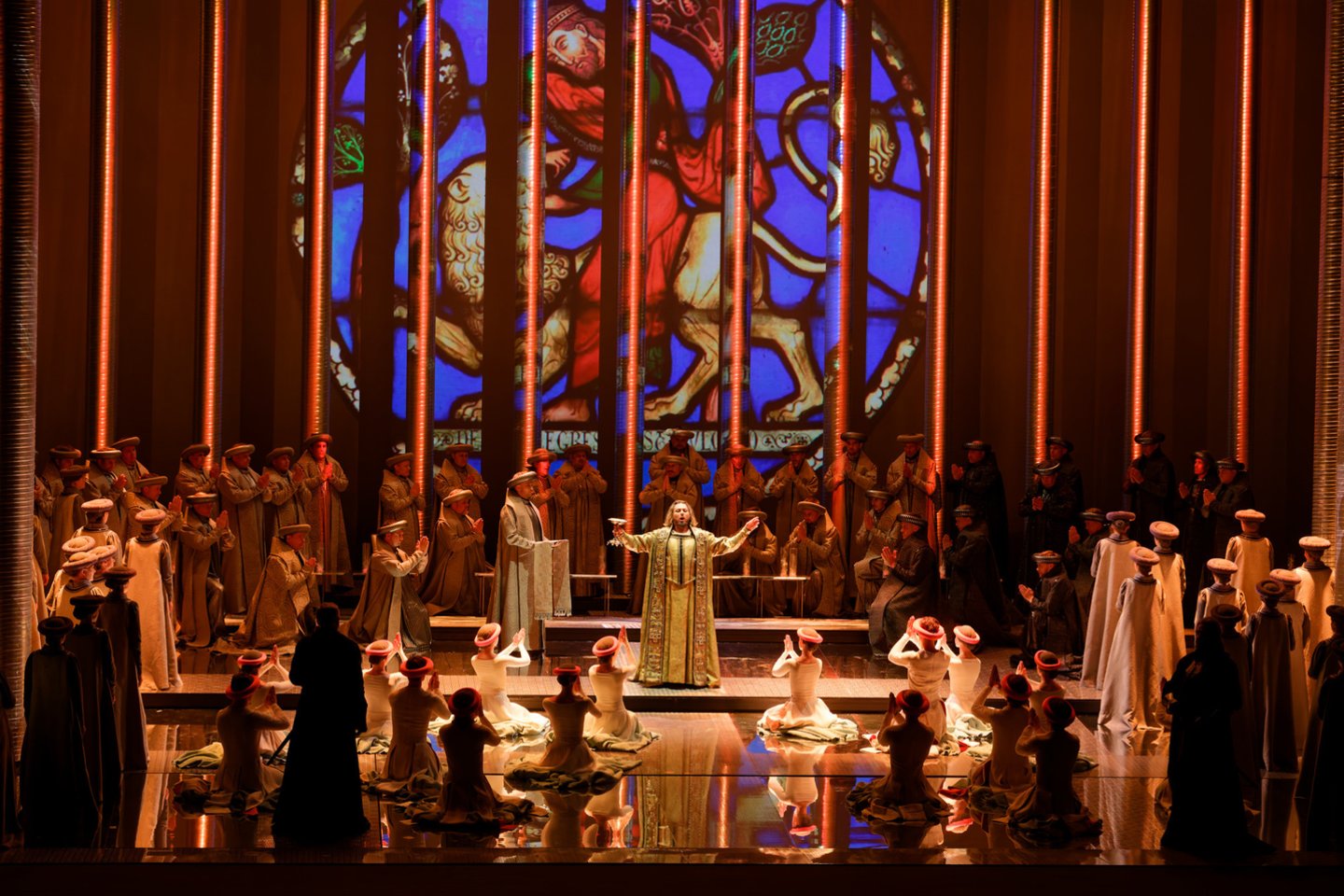 „Lietuvių“ veiksmas rutuliojasi kone abstrakčioje erdvėje – tarp futuristinių plieno kolonų, ant veidrodinių švytinčių grindų, gamtos stichijų šėlsmą vaizduojančių ir herojų būsenas atspindinčių projekcijų fone, vyraujant neutraliai spalvų paletei.<br>M.Aleksos nuotr.