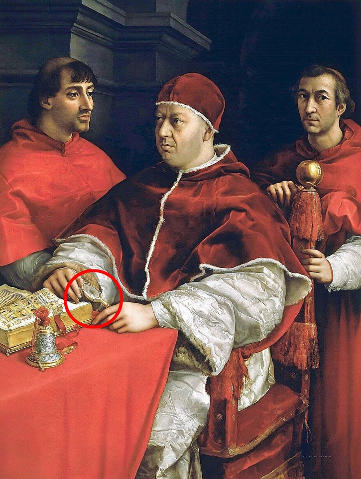 Vienas iš pirmųjų žinomų rankinių išgaubtų lęšių pavyzdžių pasirodo XVI a. pradžios popiežiaus Leono X – kuris priklausė politiškai įtakingai Medici šeimai – portrete, kurį nutapė italų meistras Rafaelis.<br> Wikimedia commons.